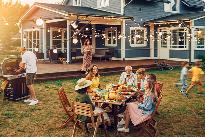 Big Family and Friends Celebrating Outside at Home. Diverse Group of Children, Adults and Old People Gathered at a Table, Having Fun Conversations. Preparing Barbecue and Eating Vegetables.